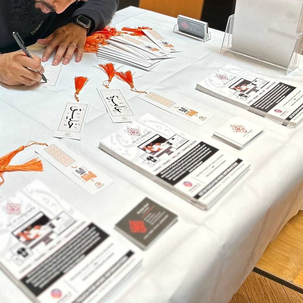 Hand-lettering personalised Arabic calligraphy bookmarks at the Art of Calligraphy table